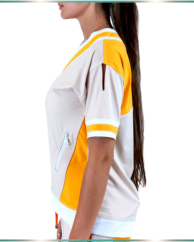 A model wearing the ivory top with orange and white stripes facing sideways showing the white, side zipped pocket and the cut out on the sleeve.