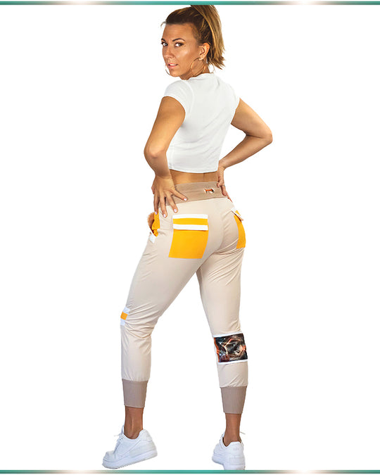 Model showing the back of the tan lounging pants with 2 flap back pockets and the artwork on the back of the pants