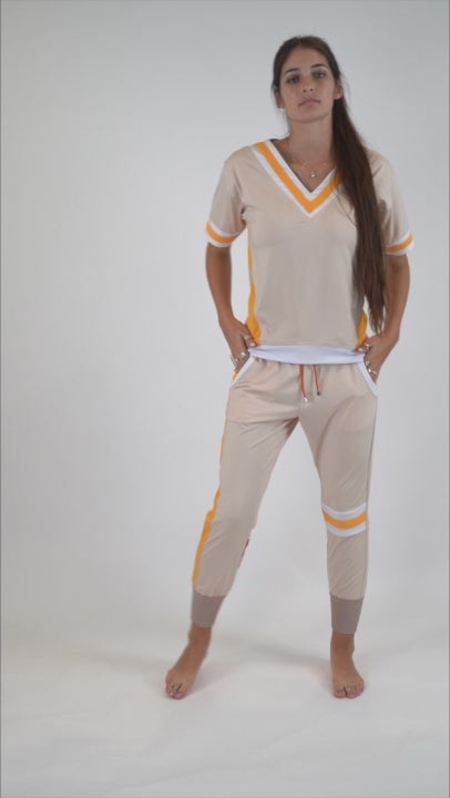 A full 360 degrees video of a model wearing the ivory top and pants set, with orange and white stripes facing forward