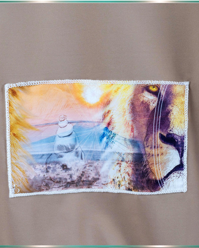 A close up of the back of the blouse, showing a patch of the artwork with the lion and a mindful rock tower with warm tones of orange, browns, yellows and blues.
